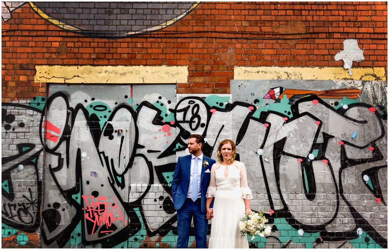Bride and groom portrait against a graffiti covered wall in Digbeth in Birmingham