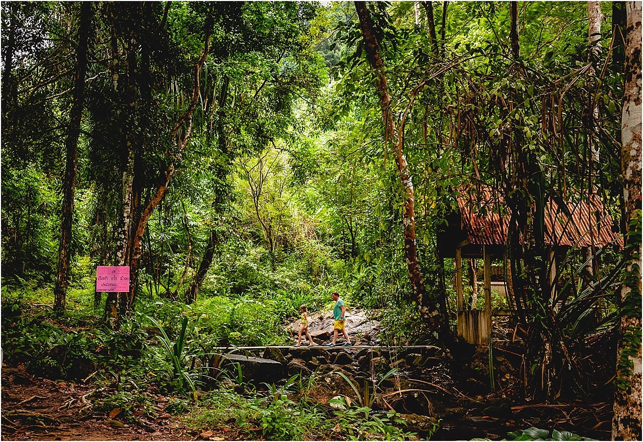 Child and father walking across bridge in the jungle at Sam Rung Waterfall