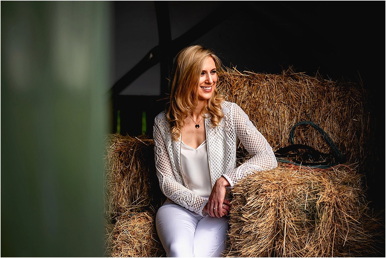 Bride sitting in barn with directional lighting on her engagement shoot
