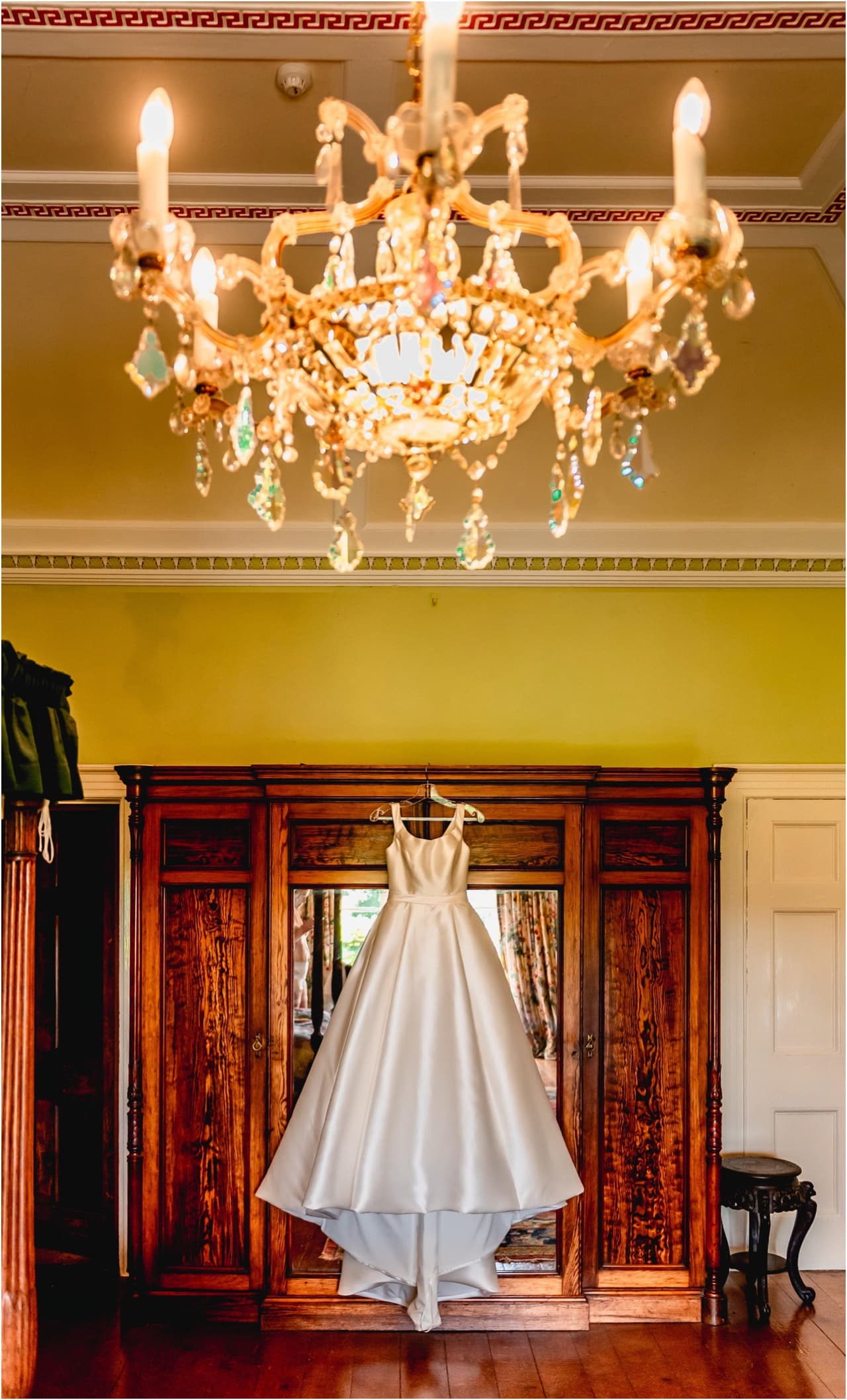Wedding dress having against wooden wardrobe with large chandelier hanging above