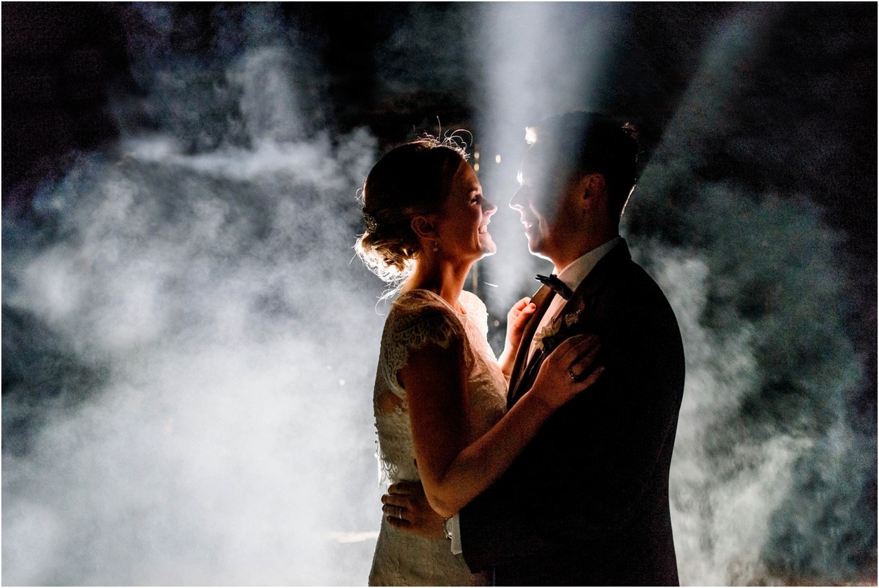 Creative night time portrait of bride and groom with fog behind the half silhouetted couple