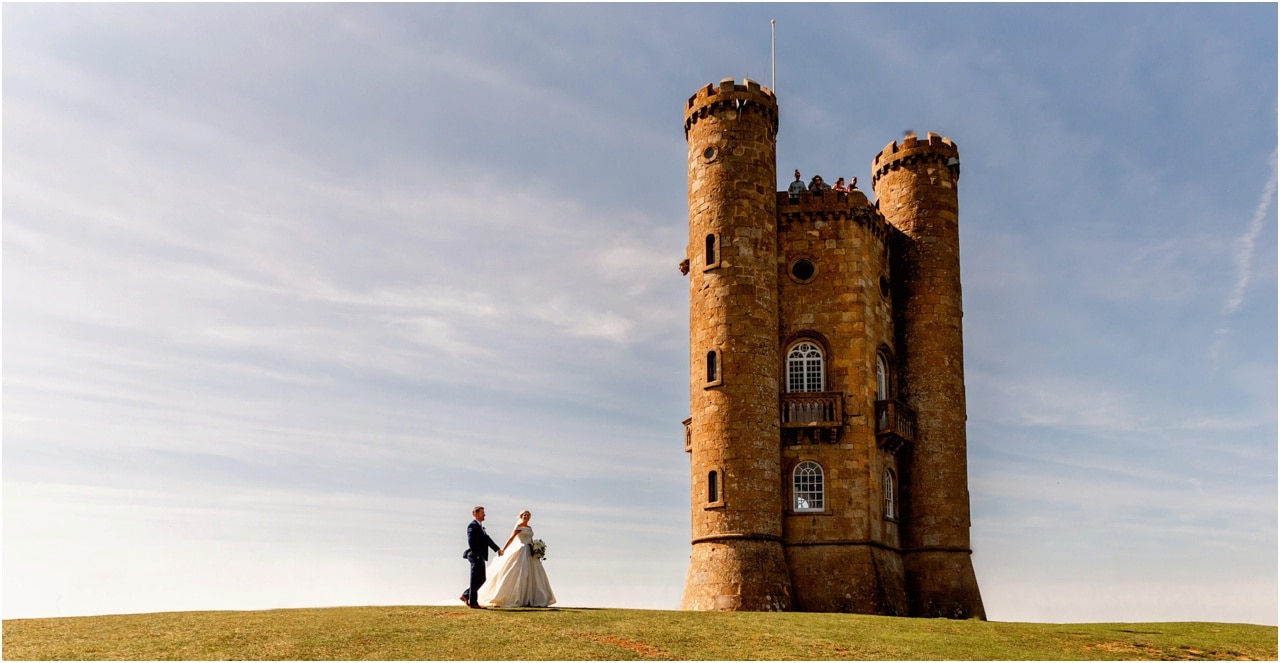 Bride and groom at Broadway Tower in the Cotswolds walking along a hillside