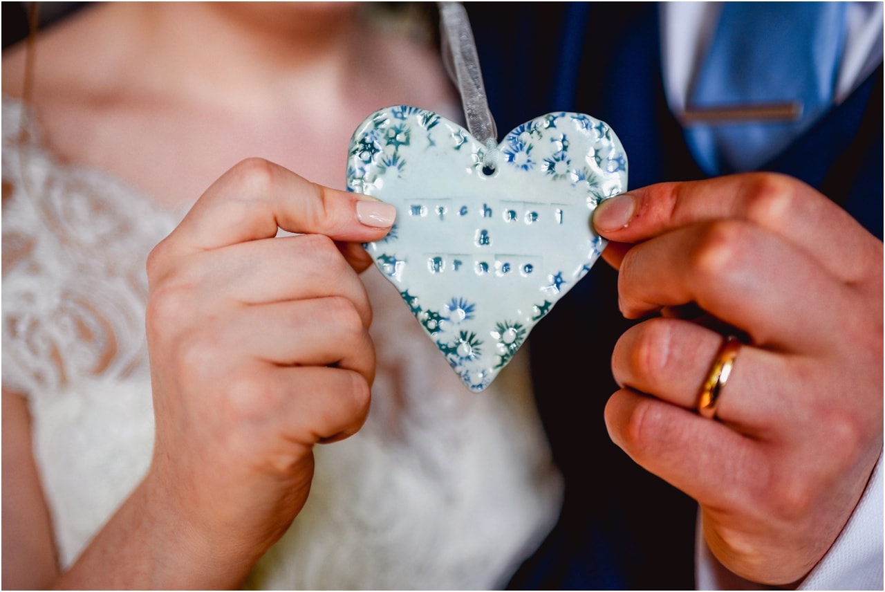 Close u pof ceramic heart being held by bride and groom commemorating their wedding day.