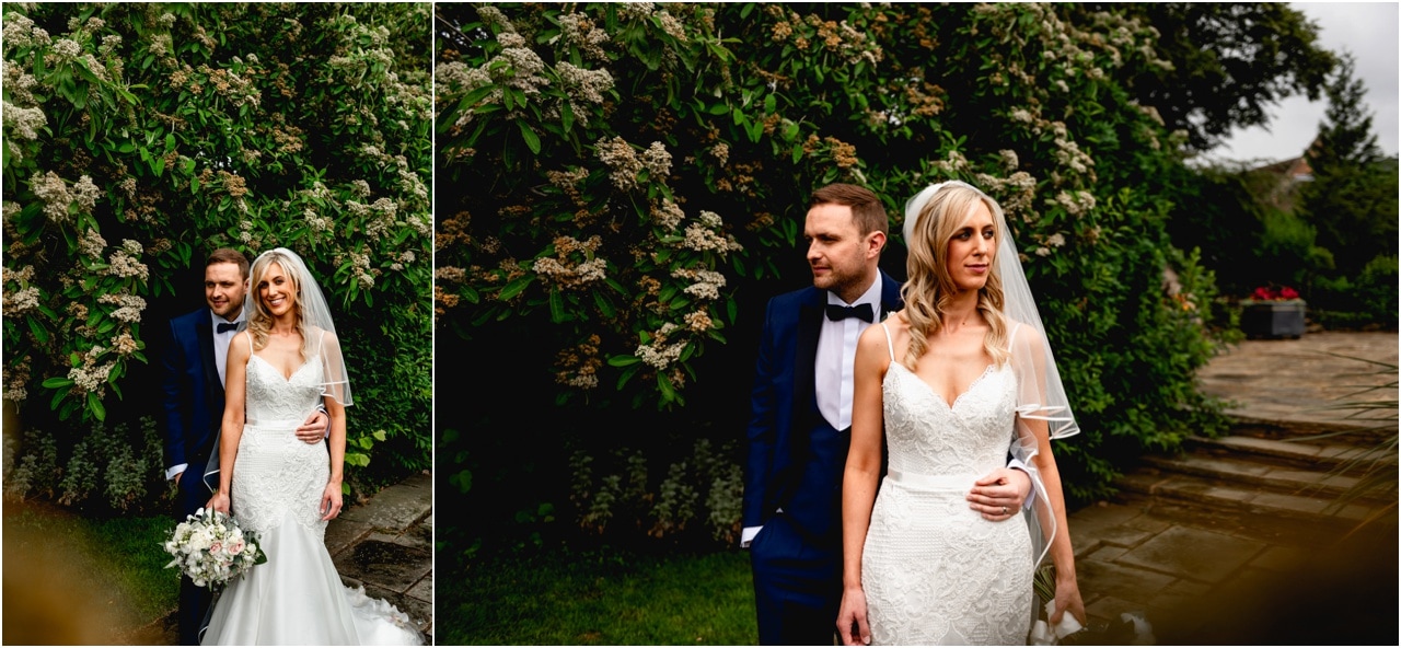 Wedding portrait photos of bride and groom against green bush outside church.