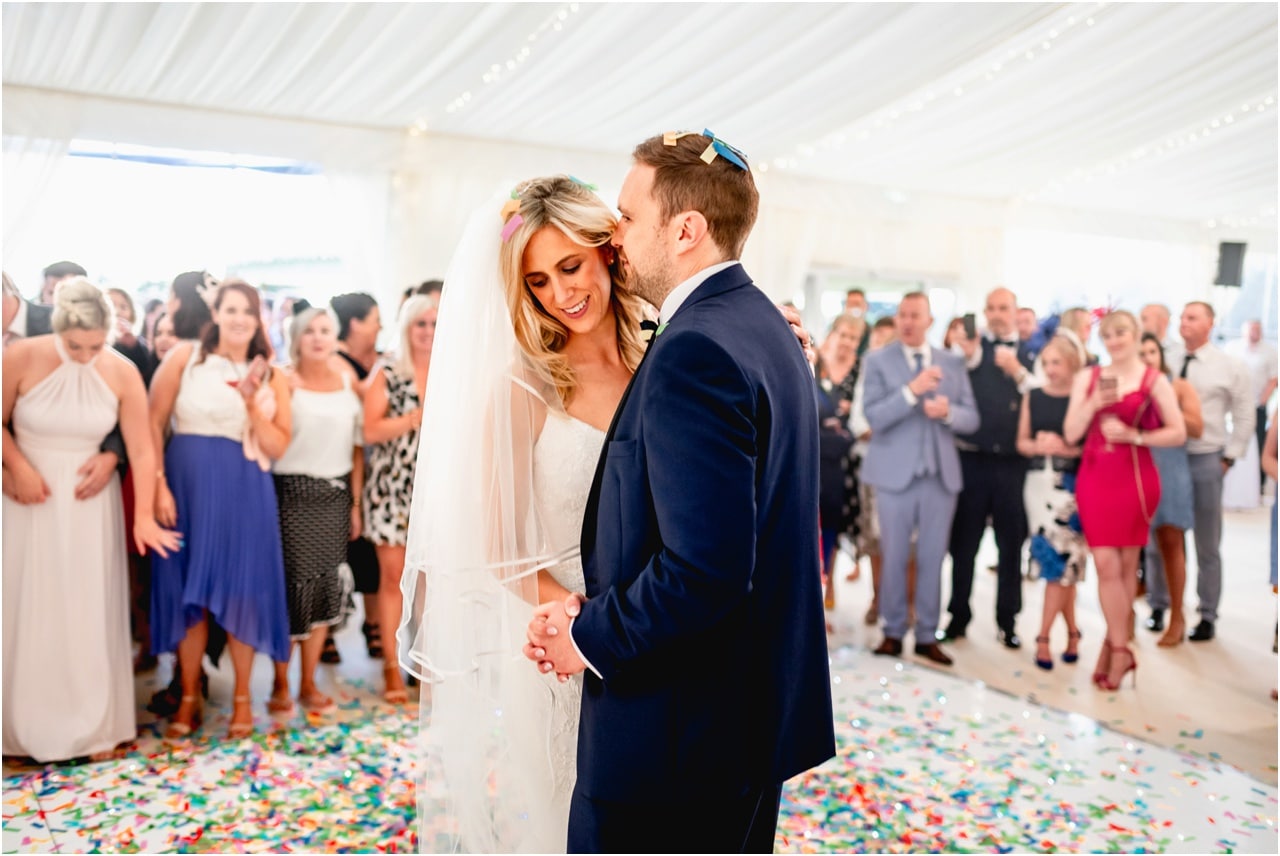 Bride and groom share their first dance with confetti cannons going off around them.