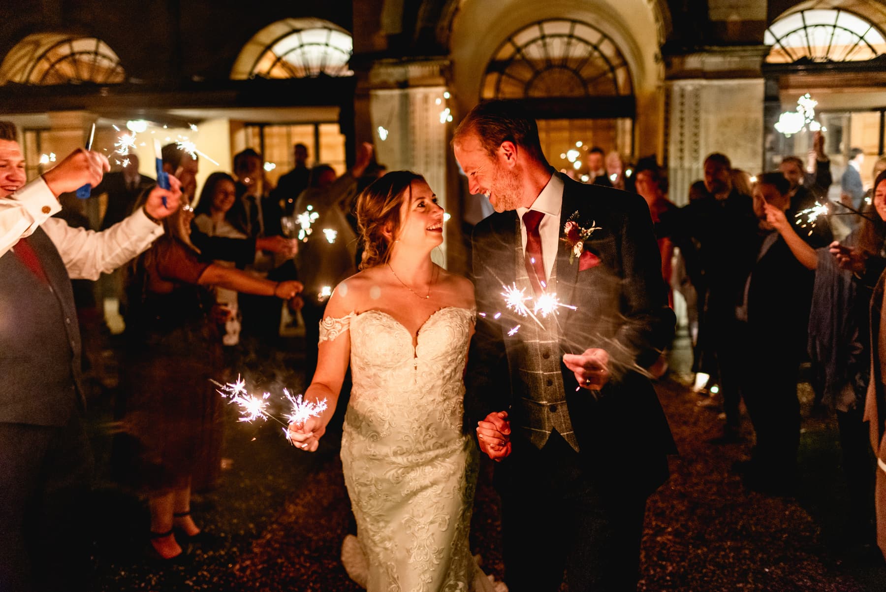 Couple walk through a tunnel of guests holding sparklers. Best Wedding Photography of 2021
