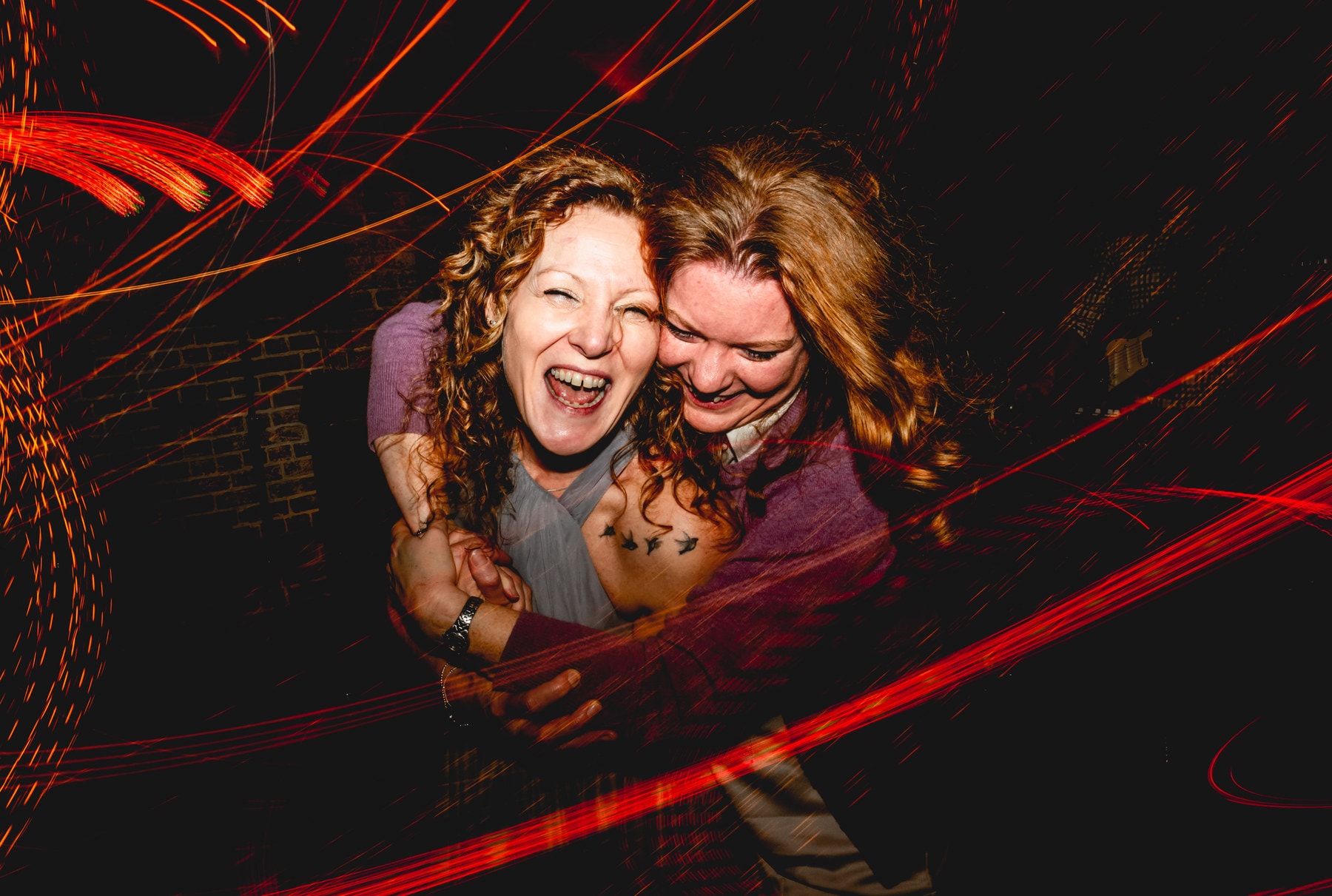 Two ladies on the dance floor laughing surrounded by light trails