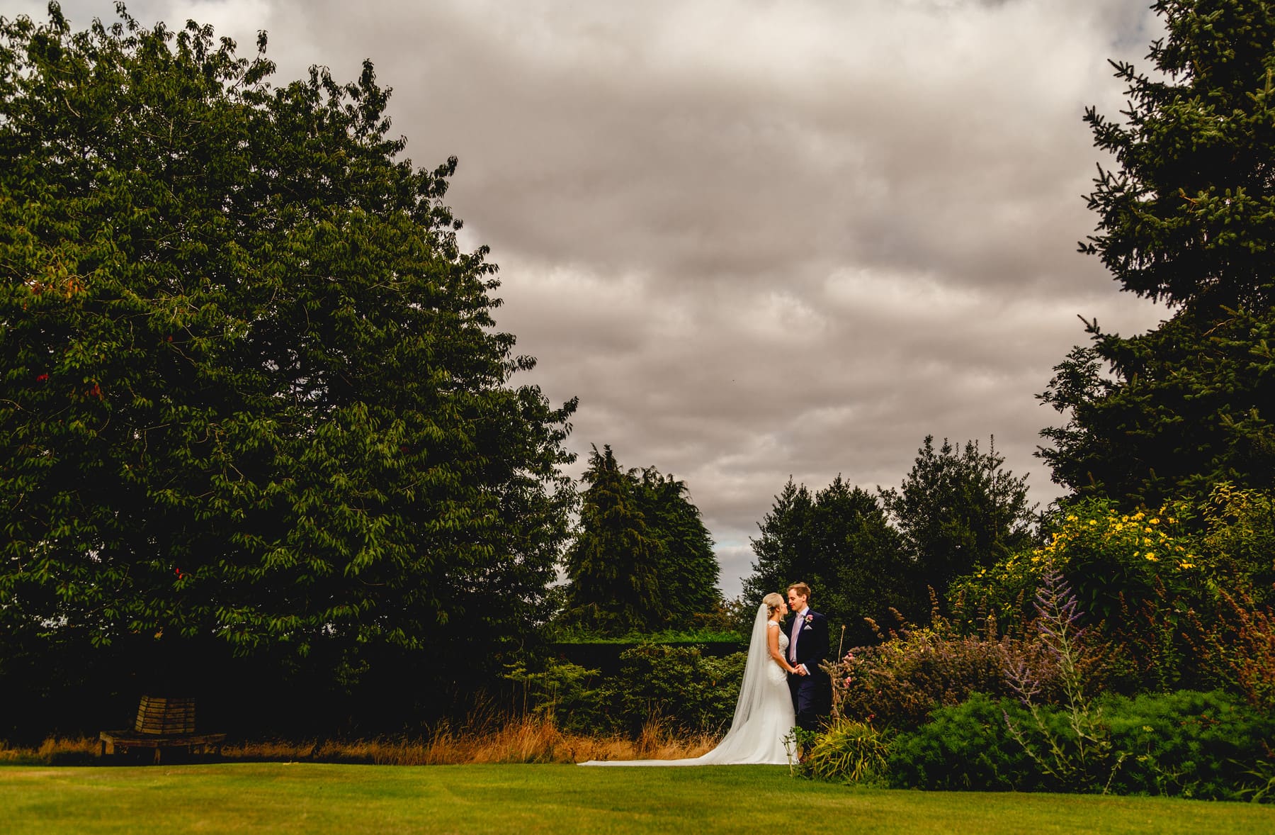 Couple face each other during a quiet moment at a wedding in the distance.