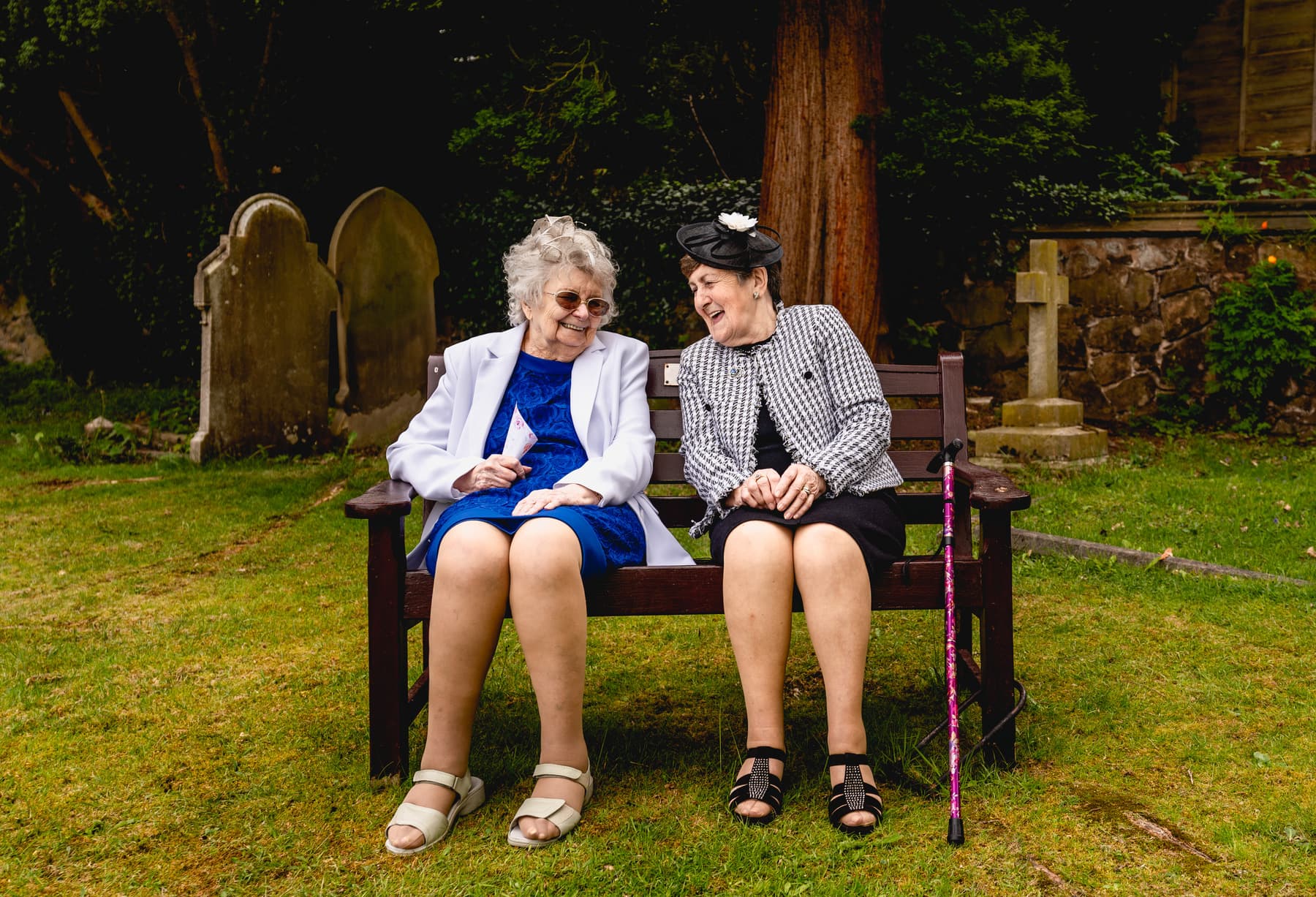 Two elderly ladies sit on a bench and laugh with each other