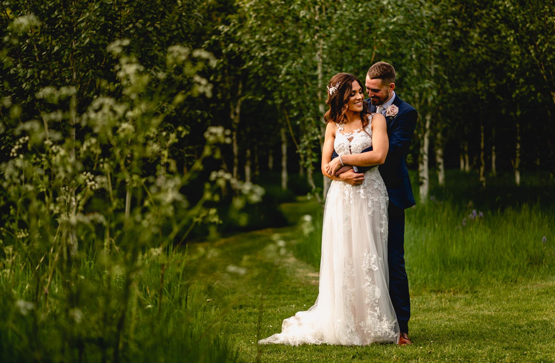 Couple cuddle on grassy path. Best Wedding Photography of 2021