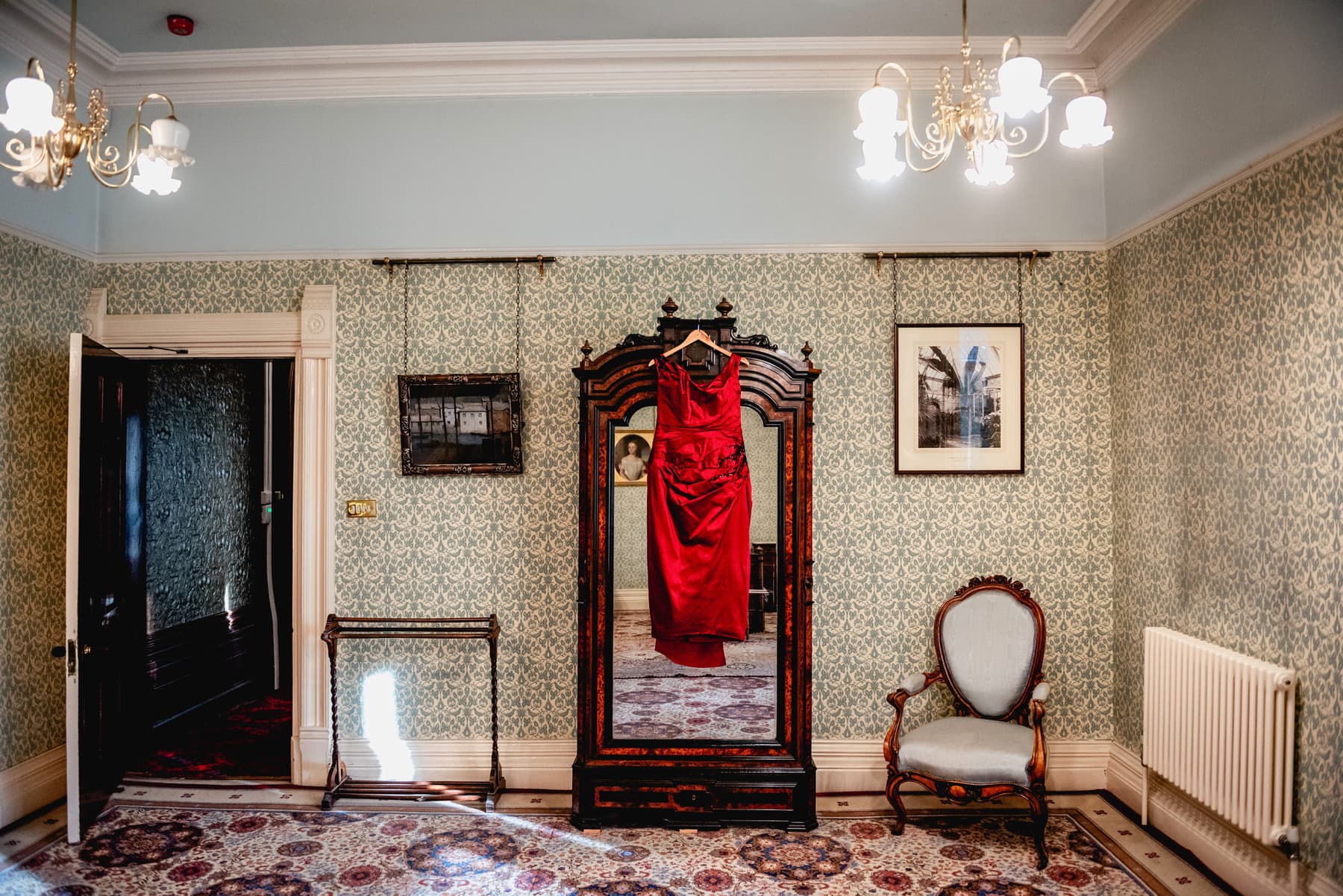 Red dress hangs in a bridal preparation suite at Highbury Hall. Best Wedding Photography of 2021