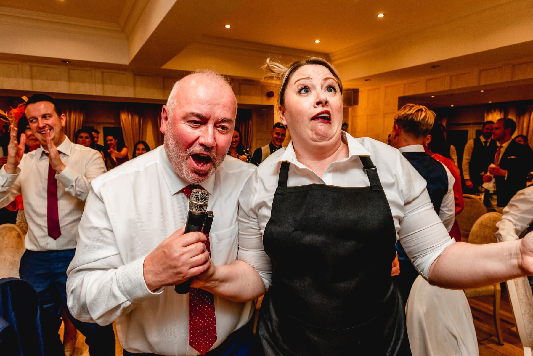 Wedding guest sings into microphone with singing waiter at a wedding at Nuthurst Grange. Best Wedding Photography of 2021