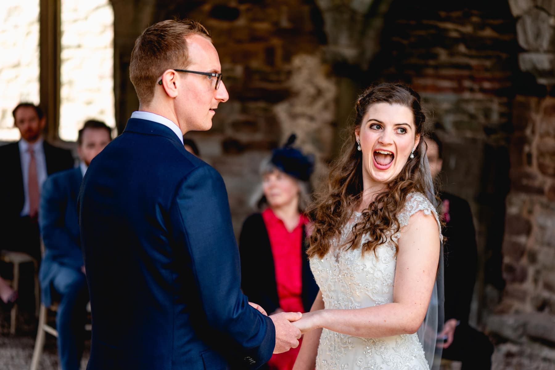 Bride laughs with mouth wide open at her wedding in a castle turret