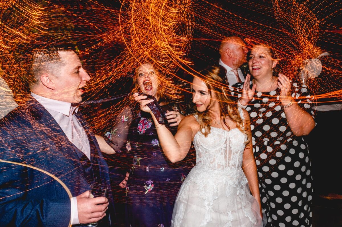 Bride dances on the dance floor at her wedding while pulling the tie of one of her wedding guests