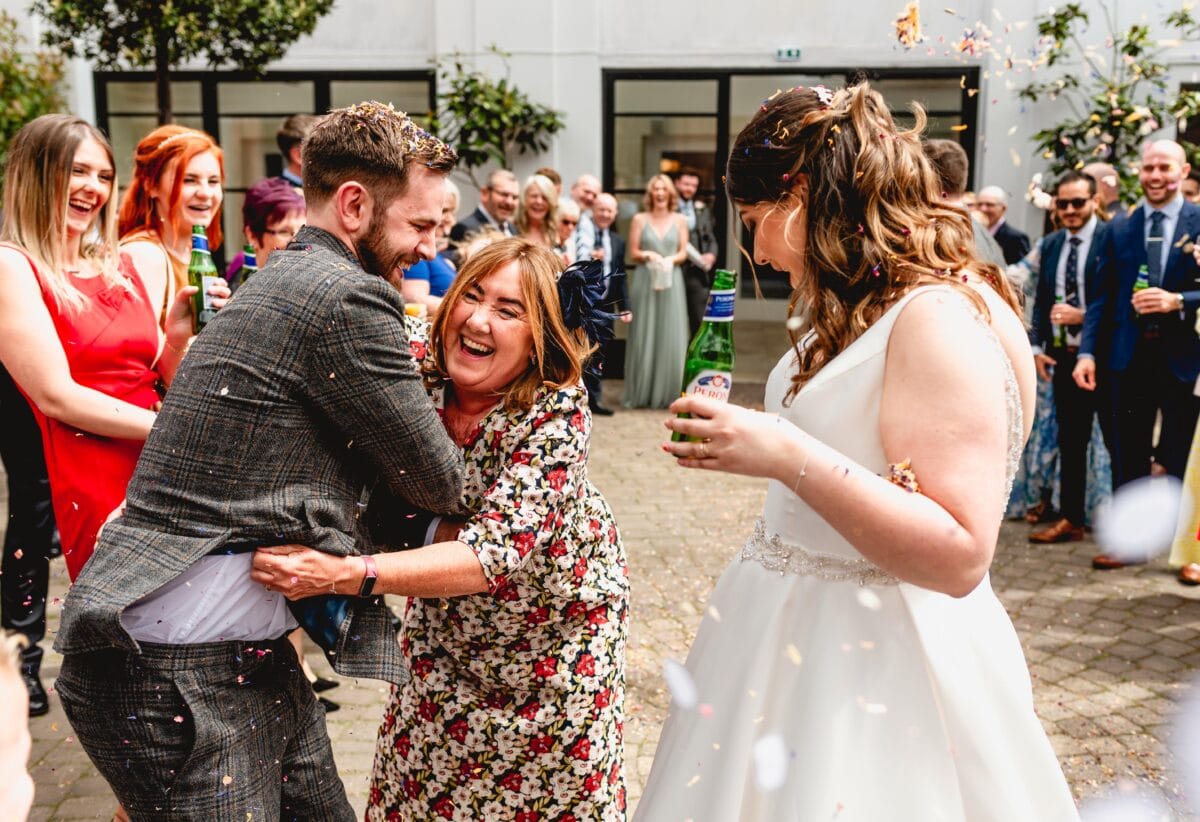 Mom of the groom laughs as she puts confetti in grooms trousers at a Fazeley Studios Wedding