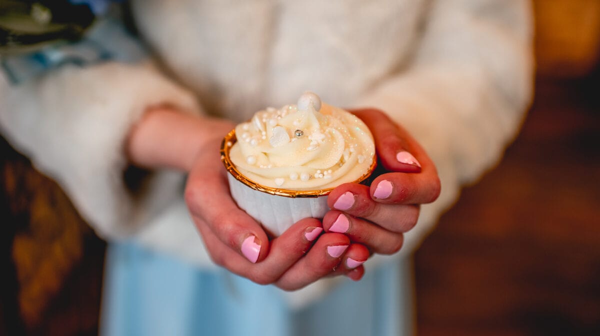 Close up photo of flower girl holding sparkly cupcake