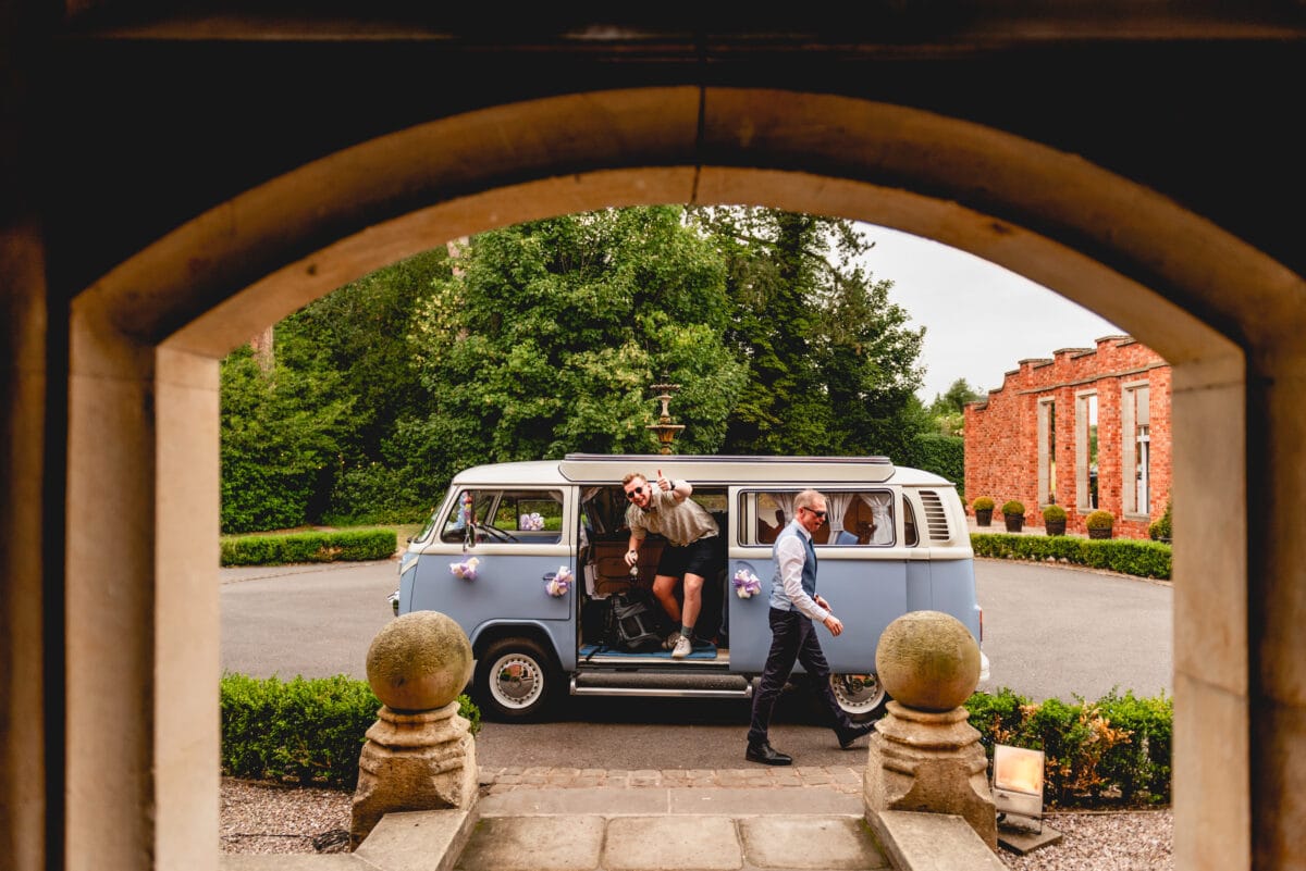 Guests depart their camper van at wedding venue. Campervan is sky blue, guest is holding a beer. Pendrell Hall, Codshall