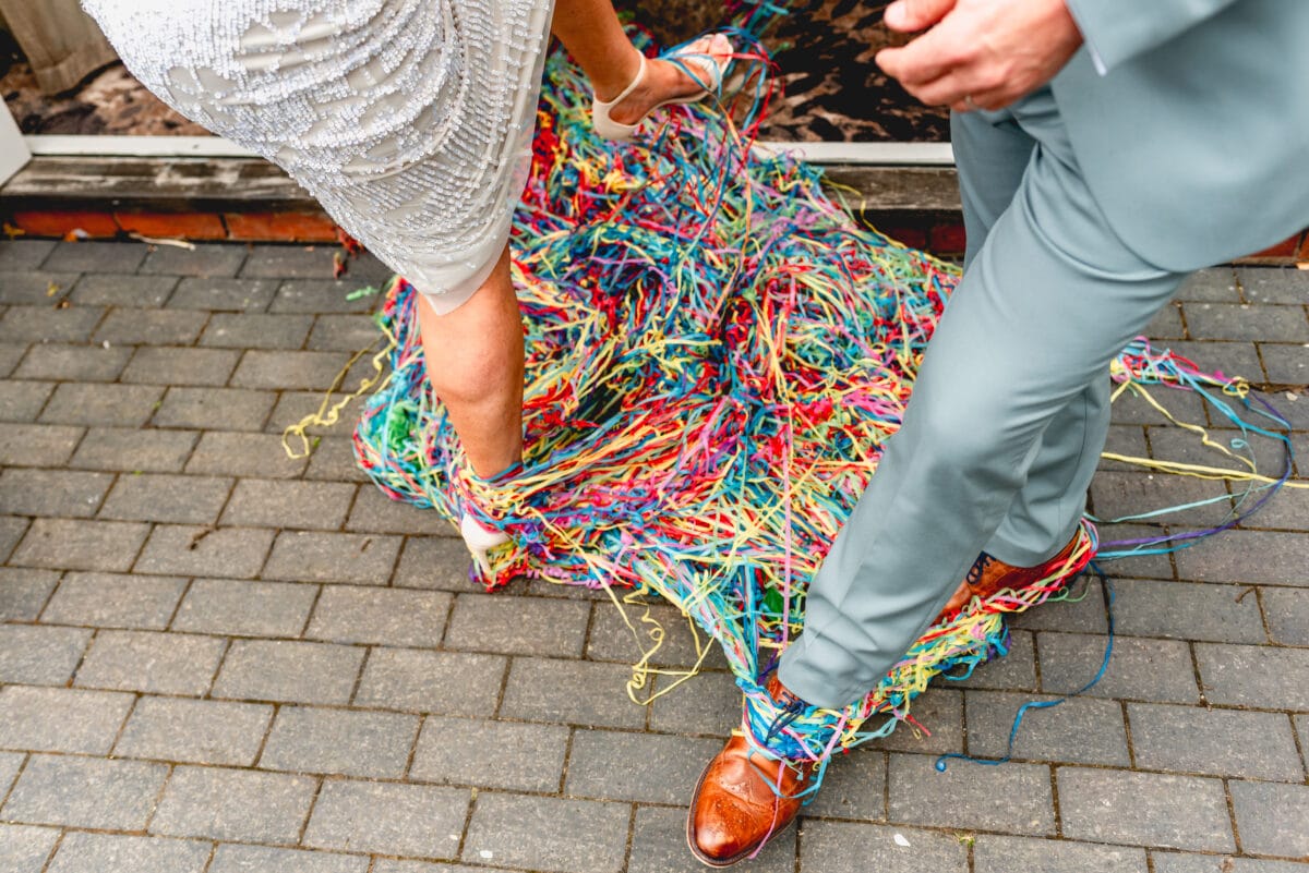 Photo of the feet of a wedding couple tangled in colourful streamers