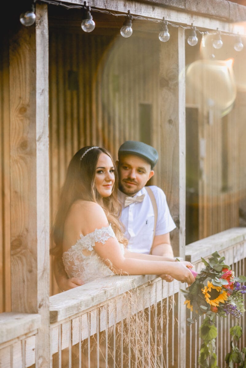 Romantic photo in fading golden light of bride and groom relaxing after their wedding on a wooden balcony