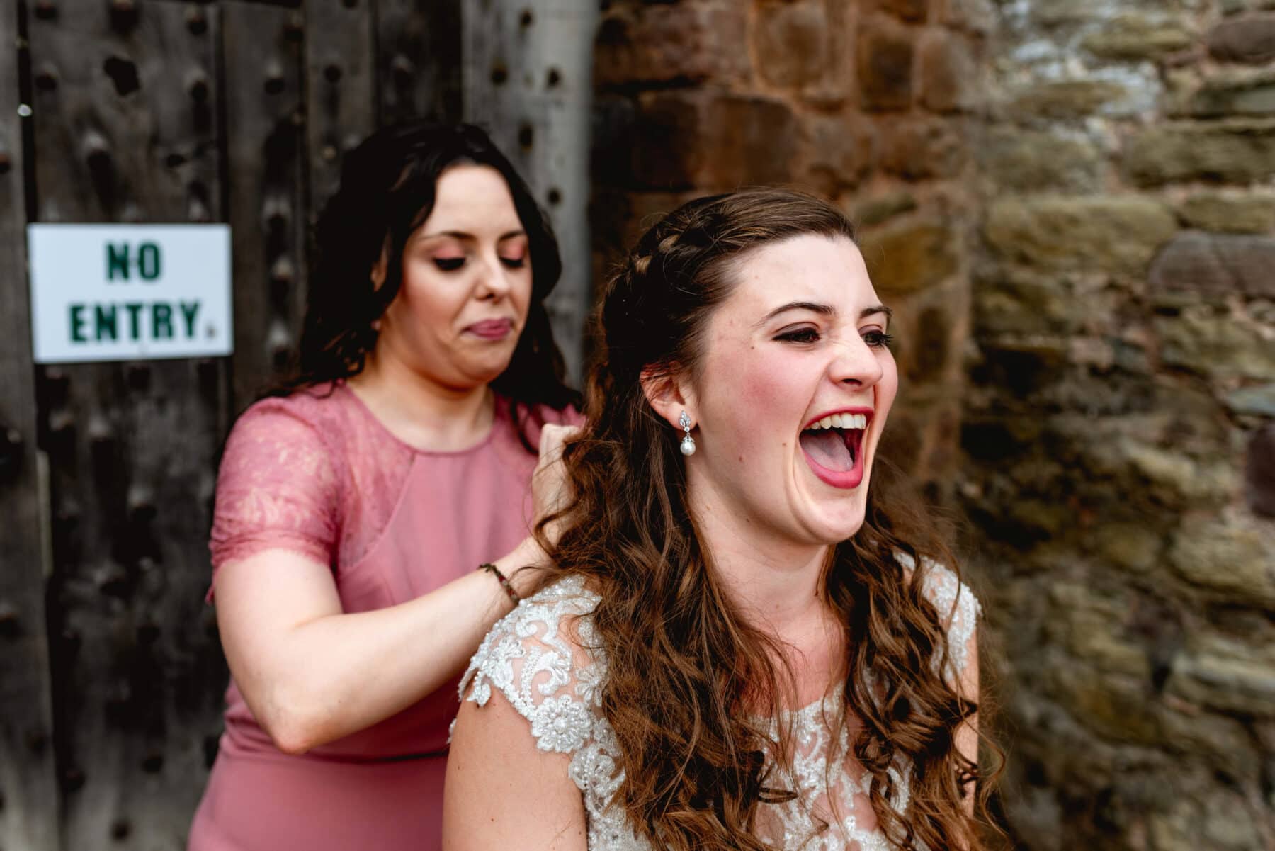 bride has her veil adjusted by bridesmaid, bride screams in pain and laughter