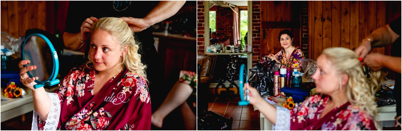 Bride has her hair styled while looking in a mirror, wearing in maroon floral dressing gown
