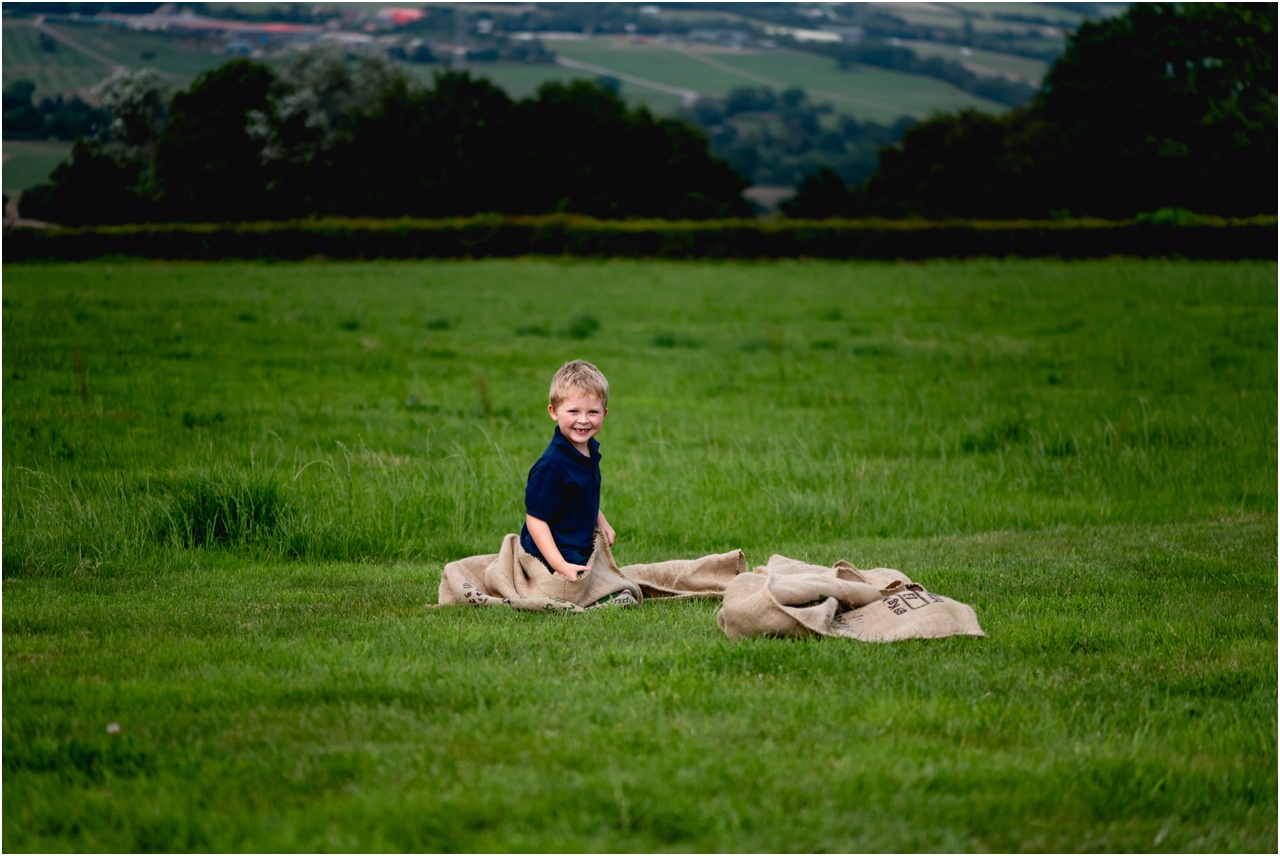 Candid photo of boy in a pile of sacks left on the grass after a sack race