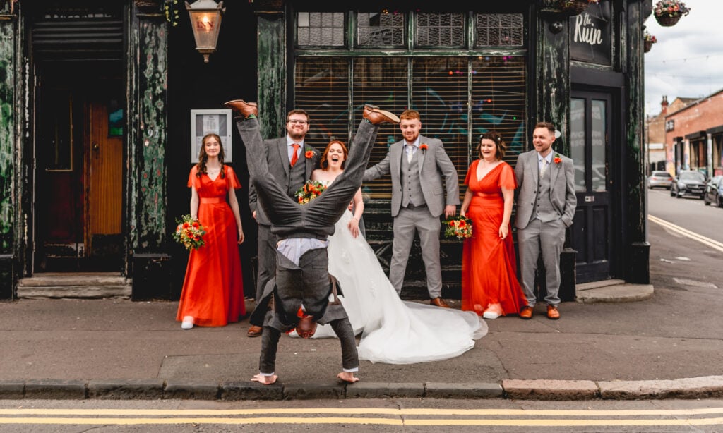 Man cartwheels in the street outside The Ruin in Digbeth while bridal party laugh