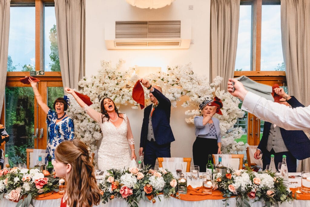 Top table wave hankies in the air and sing at Mythe Barn wedding venue in Atherstone