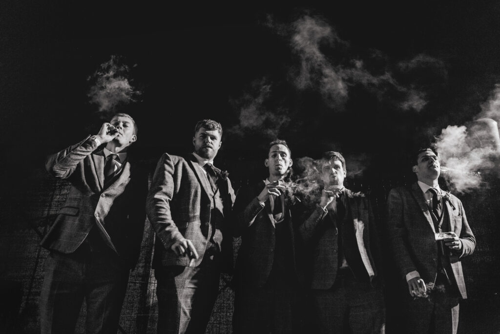 Black and white photo of groomsmen smoking cigars