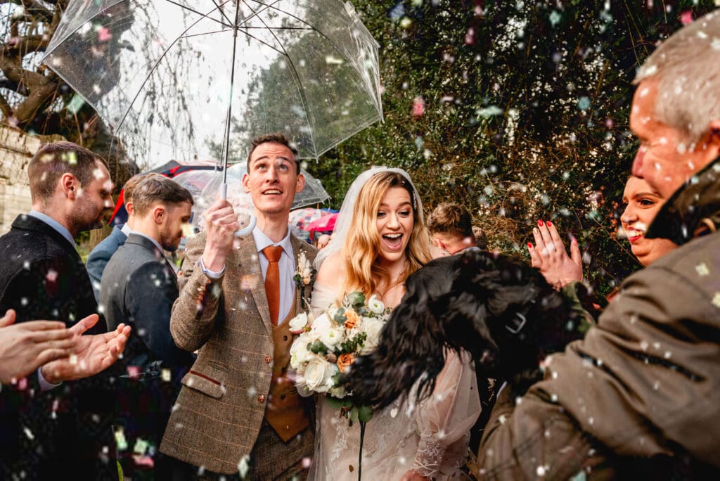 couple walk through tunnel of confetti and are greeted at the end by their dog