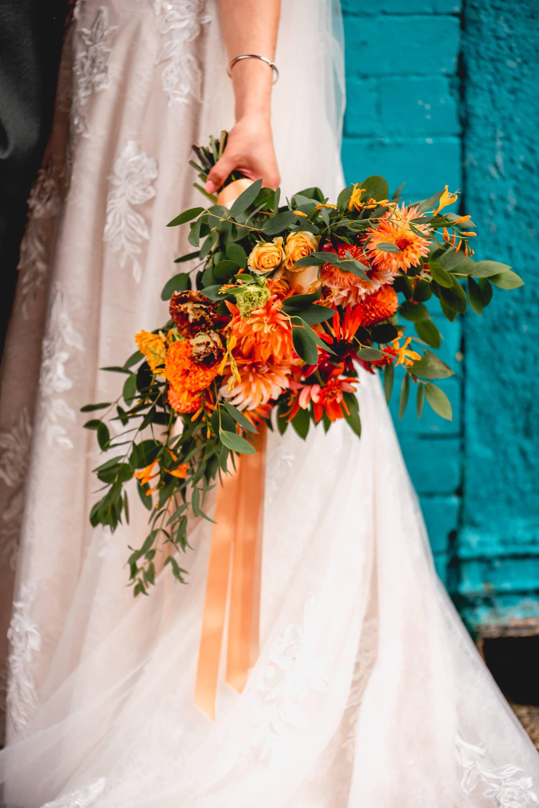 Orange bridal bouquet against a blue wall 