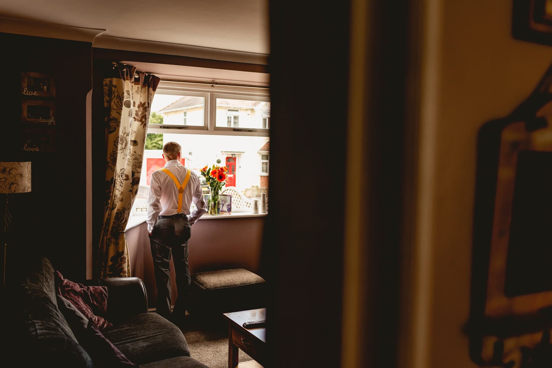 Dad waits at the window for bride at a wedding bridal preparation