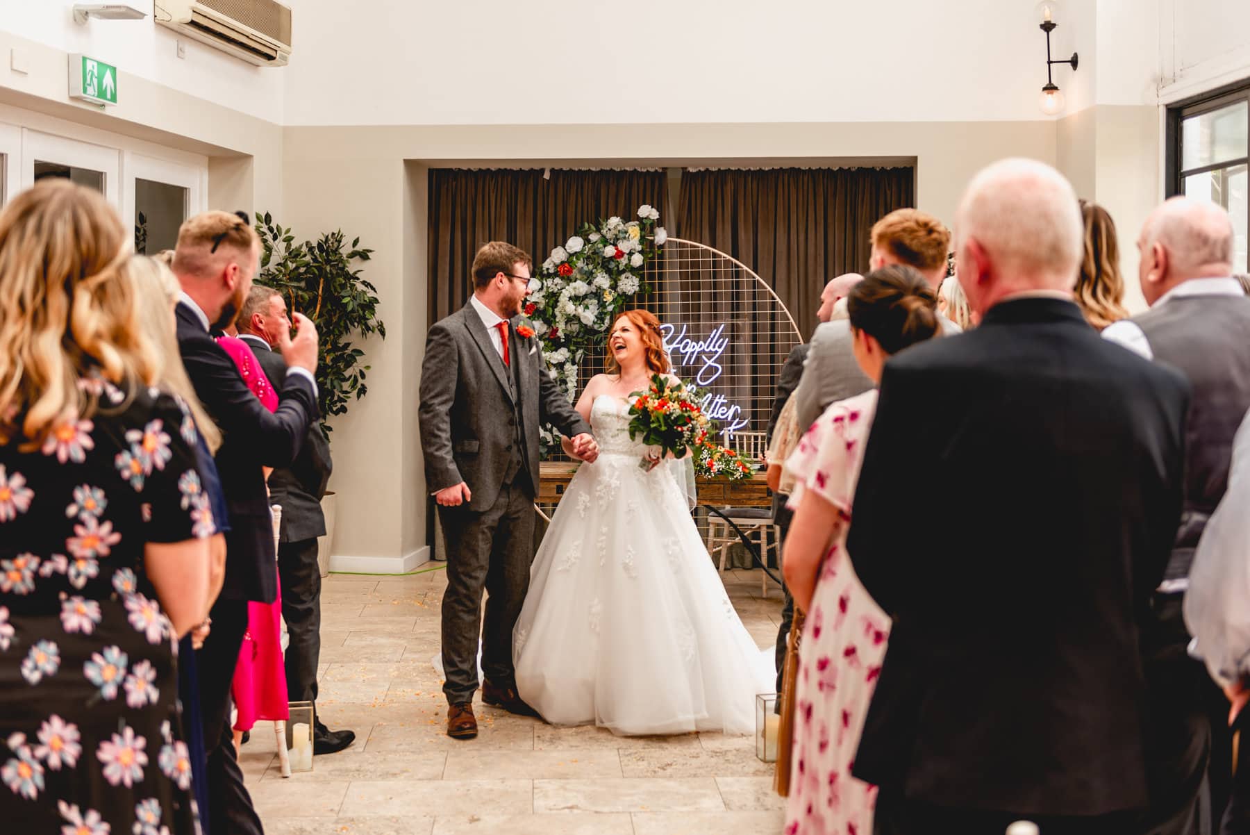Couple look at each other and laugh as they prepare to walk down the aisle together after their wedding ceremony