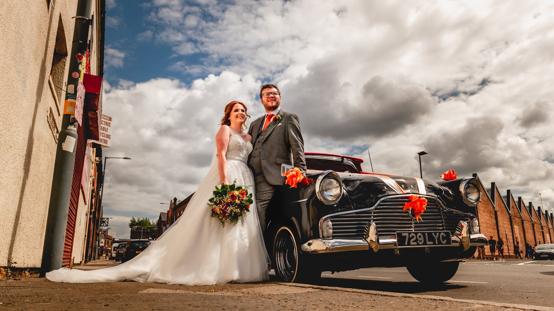 Couple portraits at a wedding with 1950's wedding car, black Zephyr with red leather interior