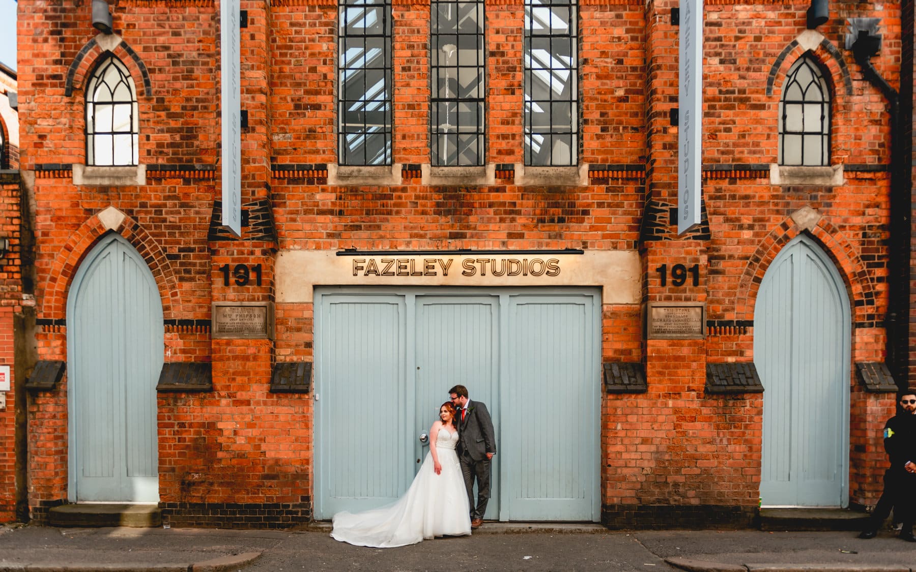 Fazeley Studios Wedding couple portrait with Hannah and Josh standing infant of the blue double doors with signage above their head