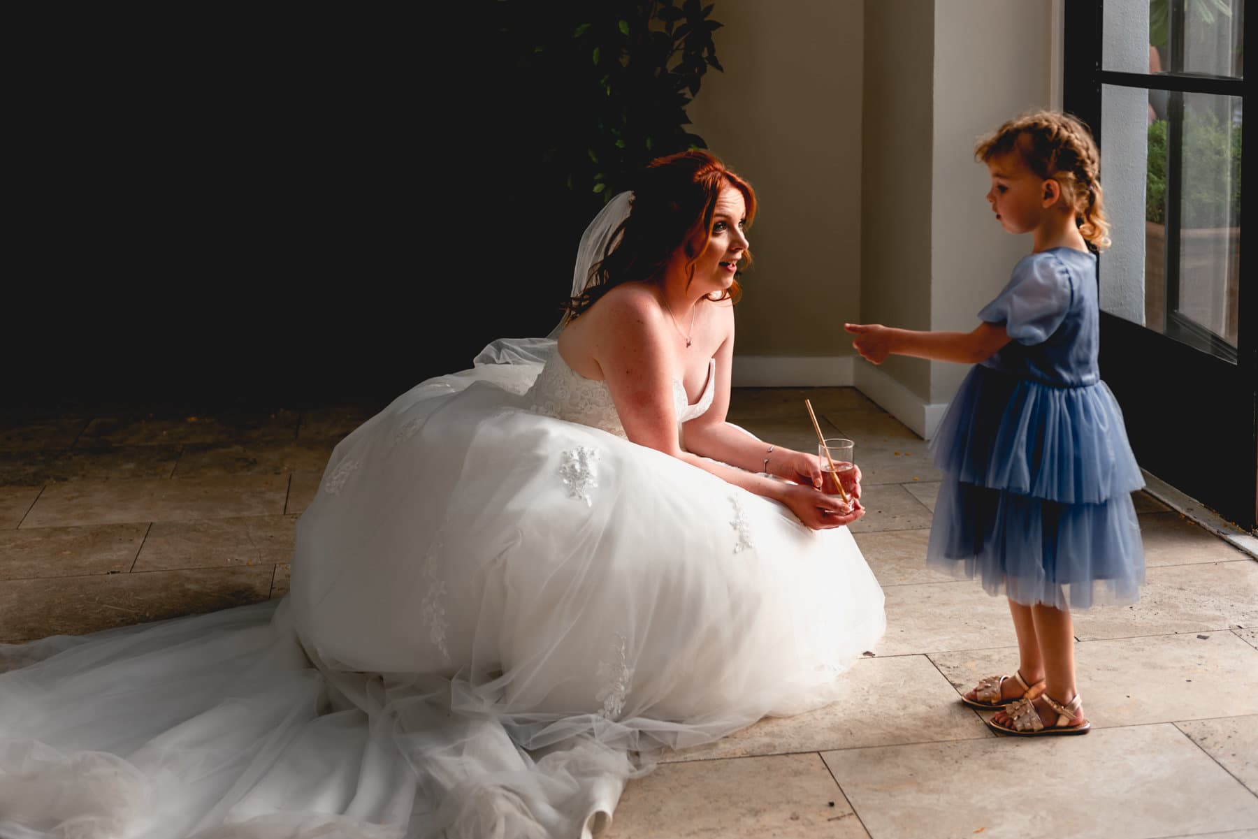 Bride chats with flower girl backlit by the sun