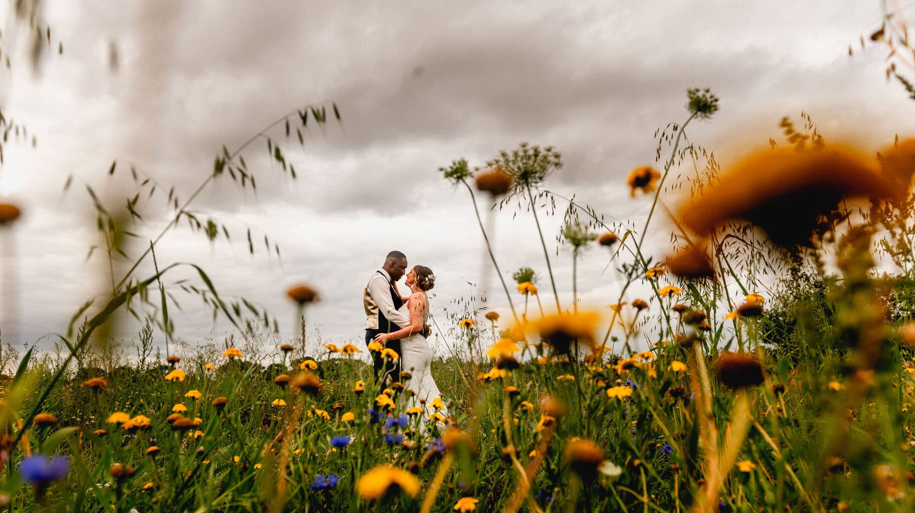 Wild flower field with bride and groom at Mythe Barn Wedding Venue