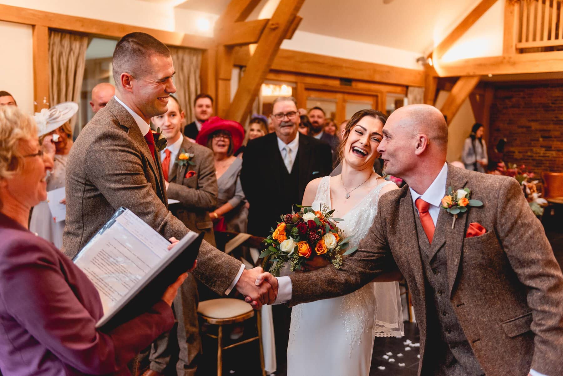 Bride and her father laugh at the wedding ceremony at Mythe Barn