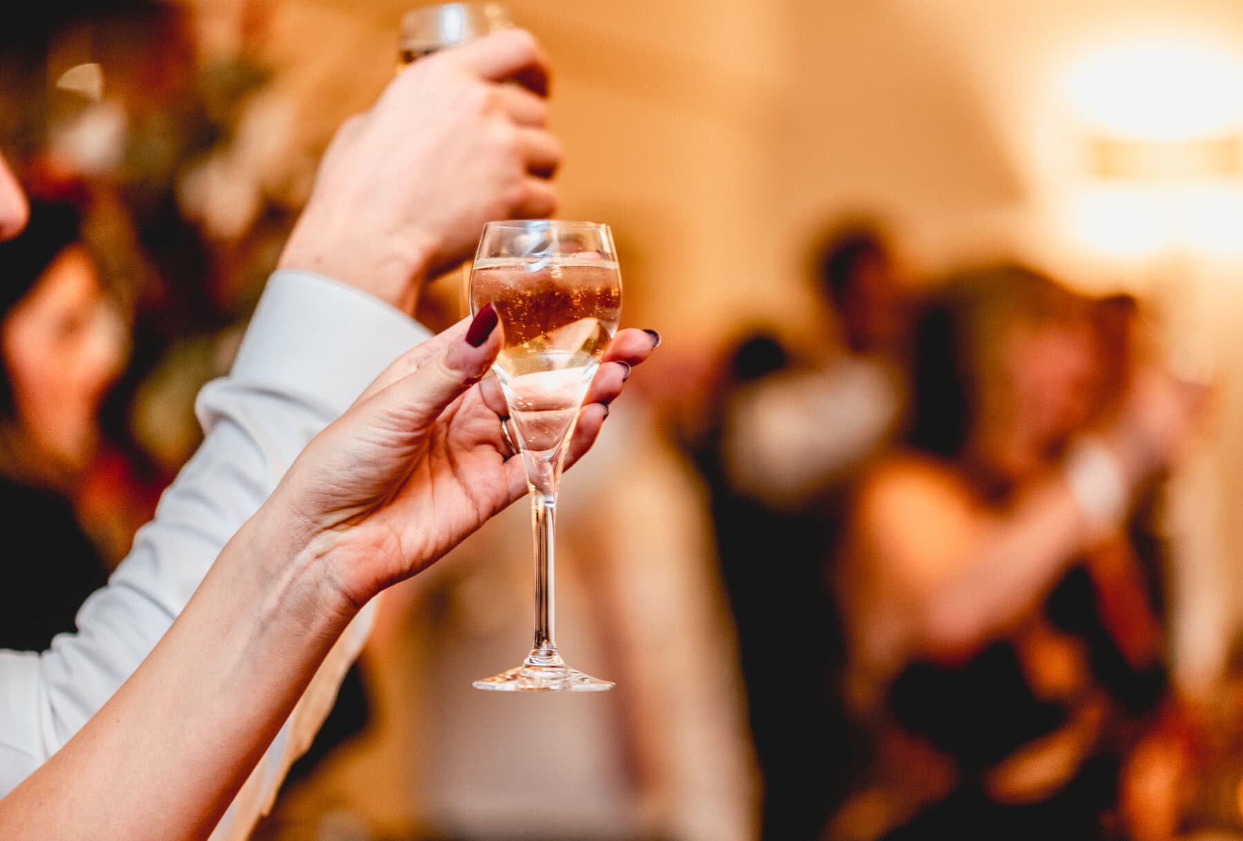 champagne glasses filled with champagne raised in the air