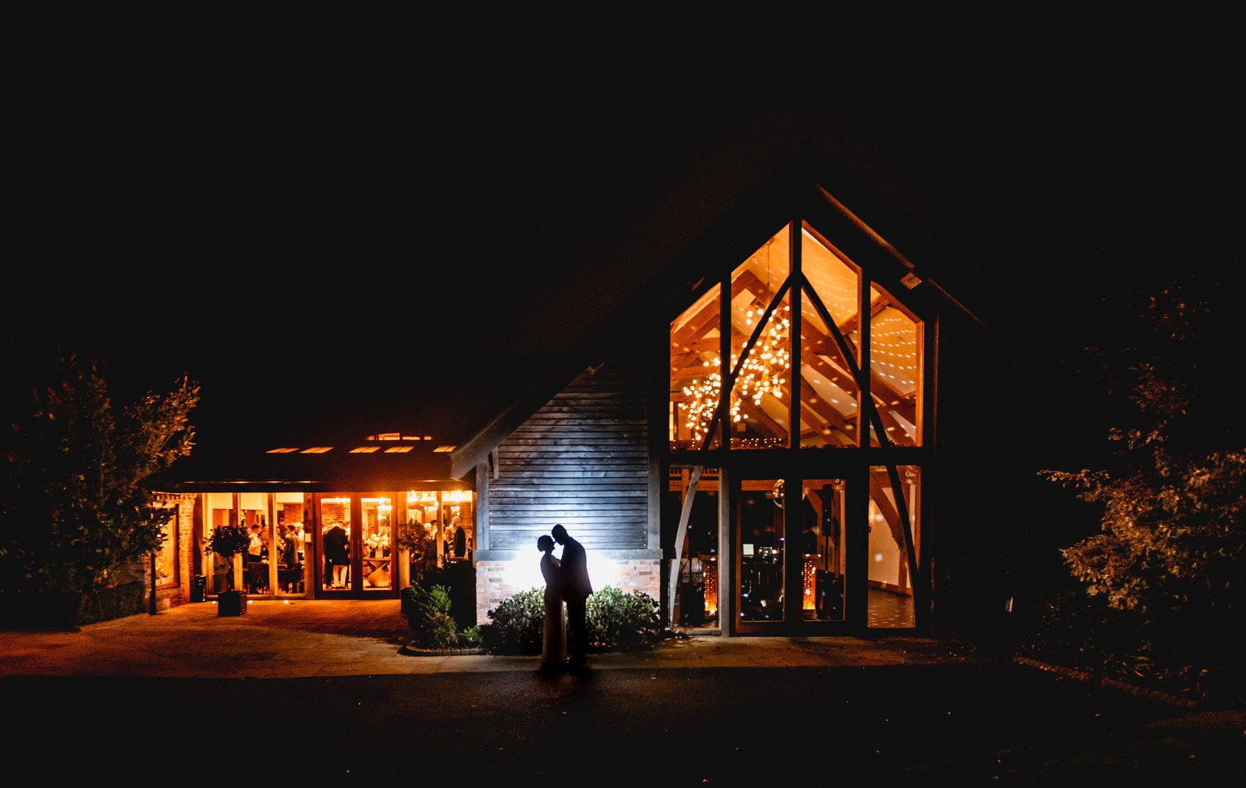 silhouette of bride and groom outside Mythe Barn wedding venue at night time