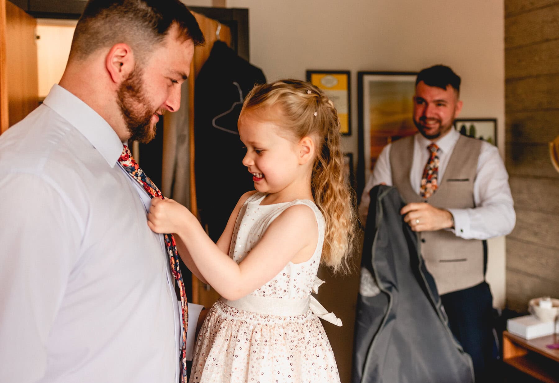 Flower girl does up her father's tie before a wedding at Swallows Nest Barn