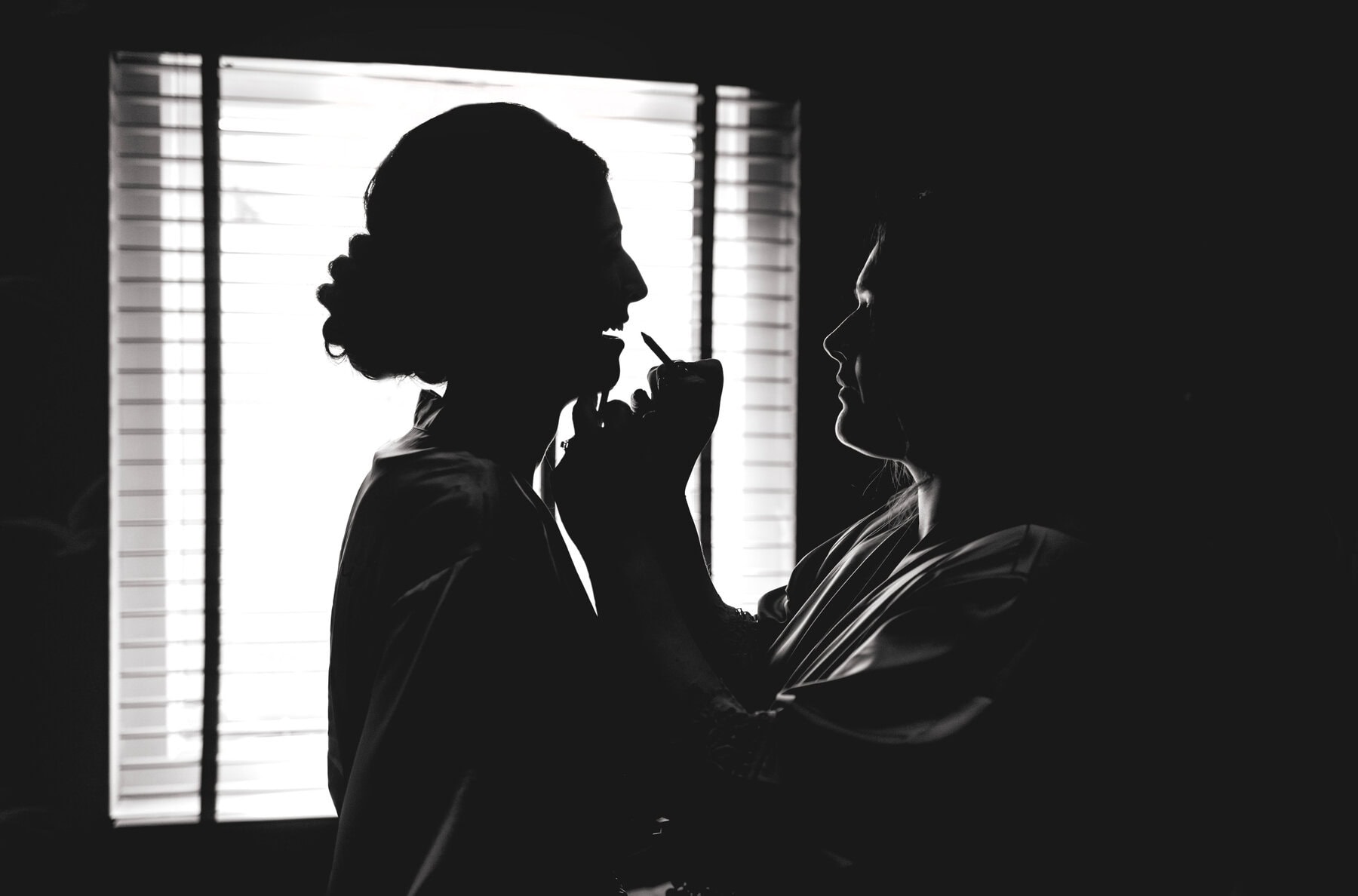 Black and white silhouette photo of bridesmaid having lipstick applied