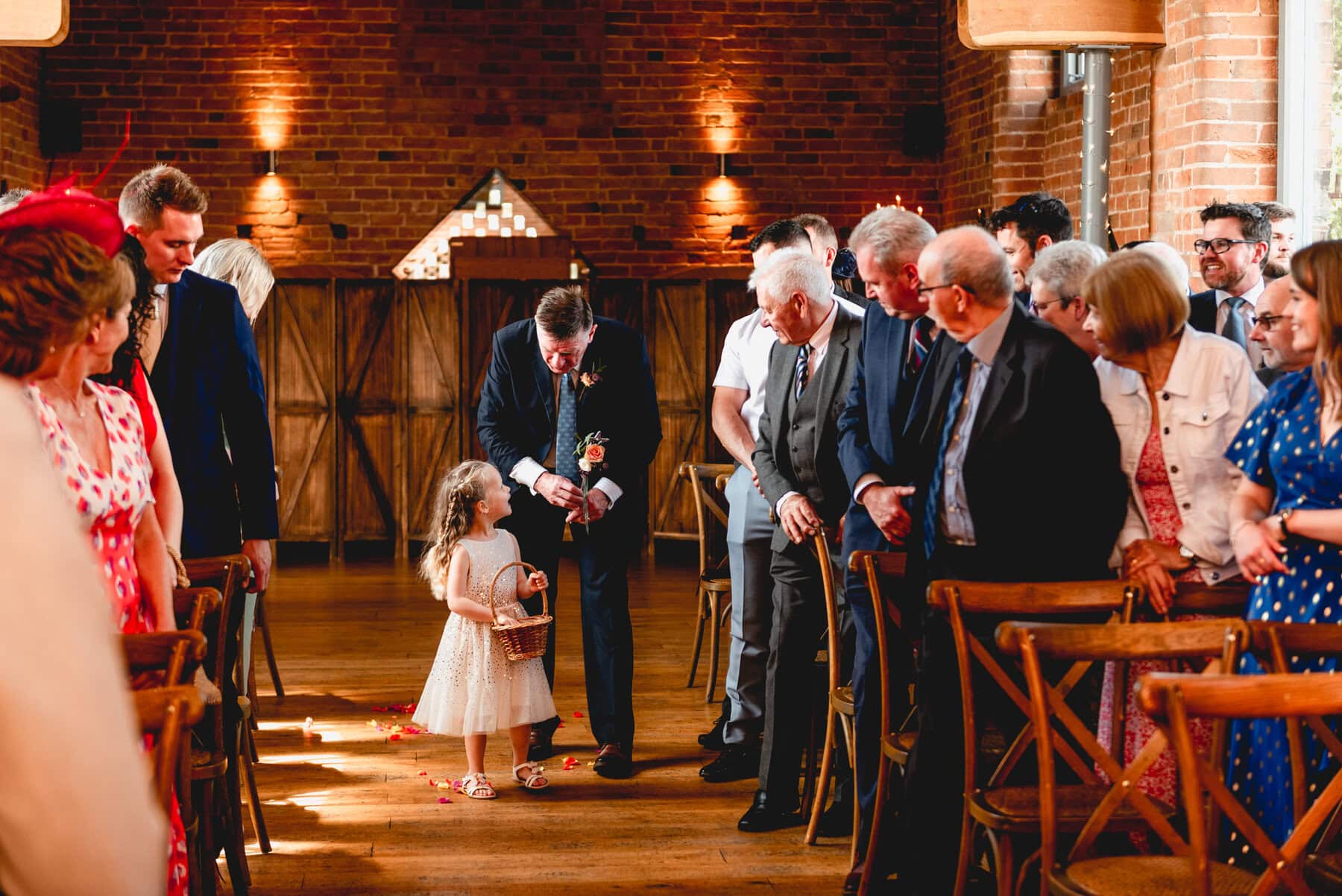 Flower girl walks down aisle before wedding ceremony to scatter flower petals with help from her Grandad