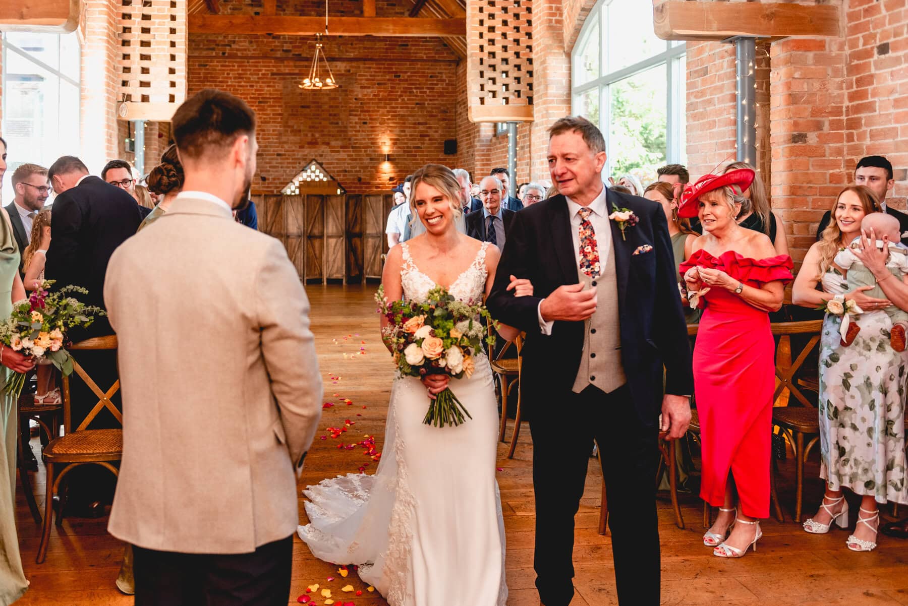 Bride and groom see each other at the end of the aisle before wedding ceremony at Swallows Nest Barn