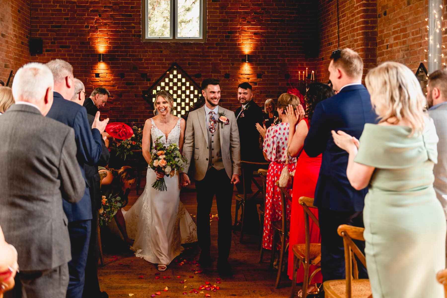 Couple walk down aisle to cheers of delight after their wedding ceremony at Swallows Nest Barn