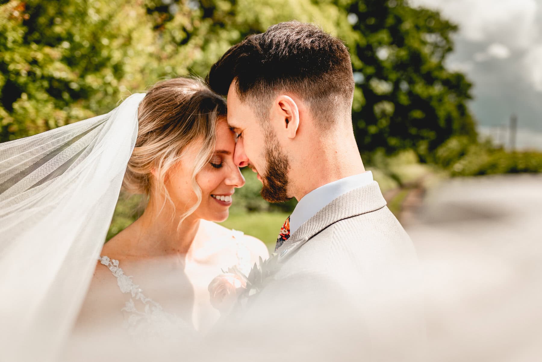 Portrait of couple on their wedding day surrounded by veil