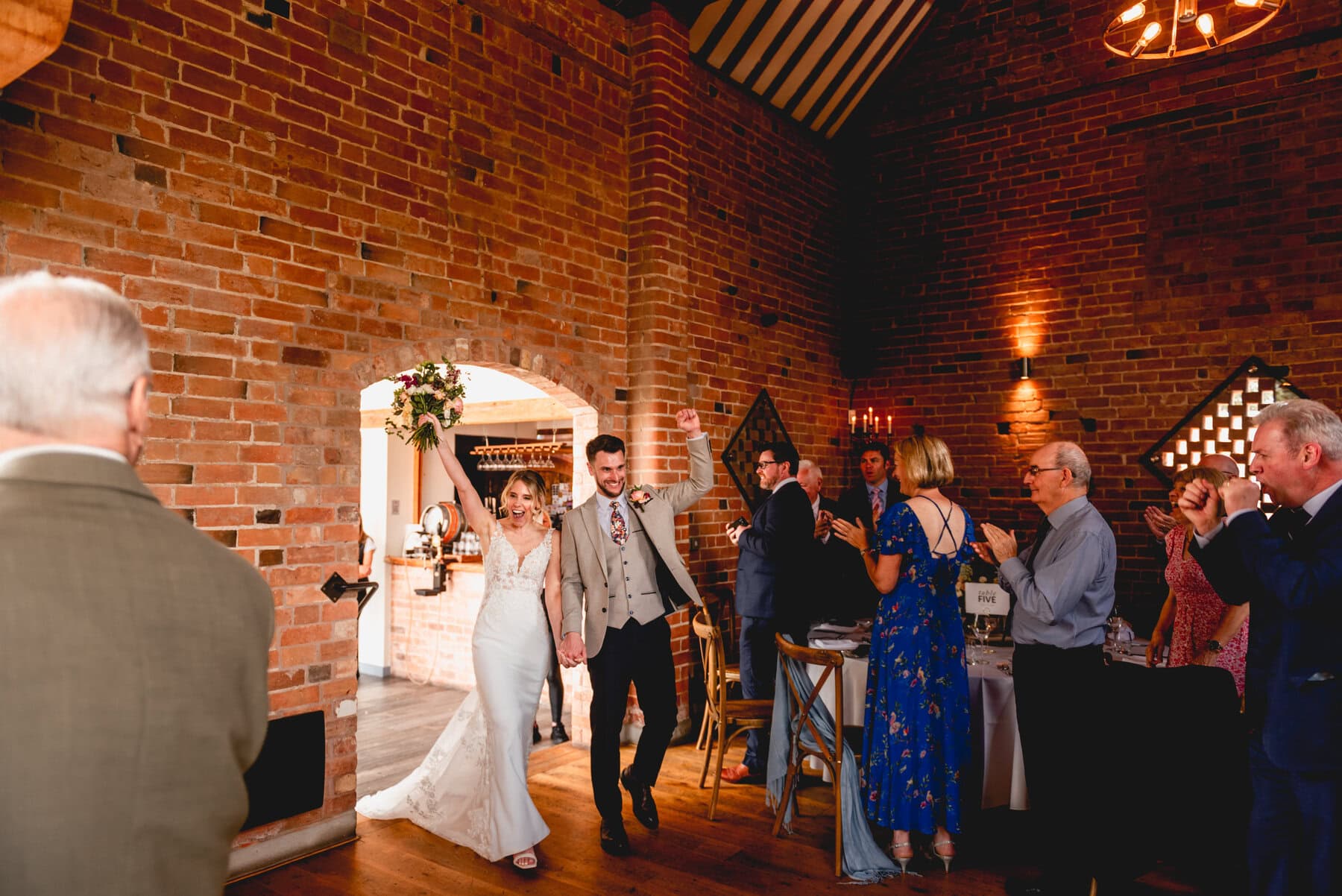 Couple enter wedding breakfast to cheers as they raise their hands and pump fists in the air