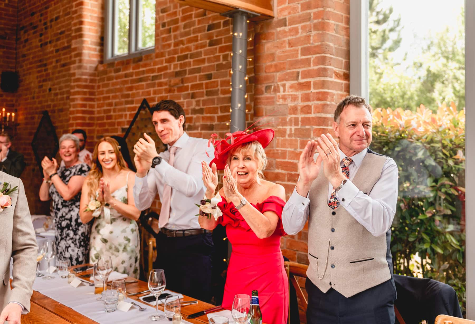 Guests at a top table cheer as the couple enter their wedding breakfast