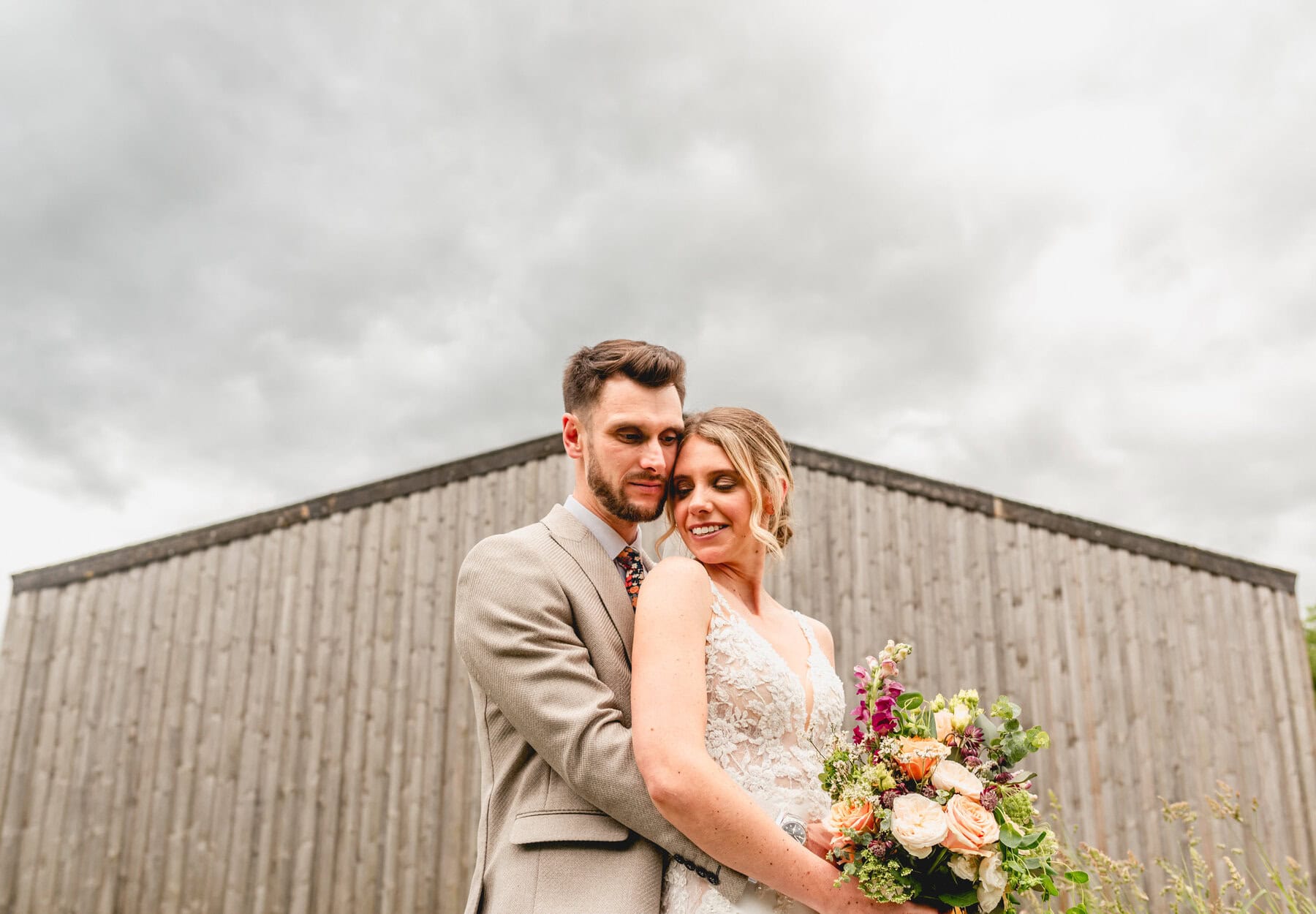 Portrait of bride and groom against the backdrop of a barns pointed roof