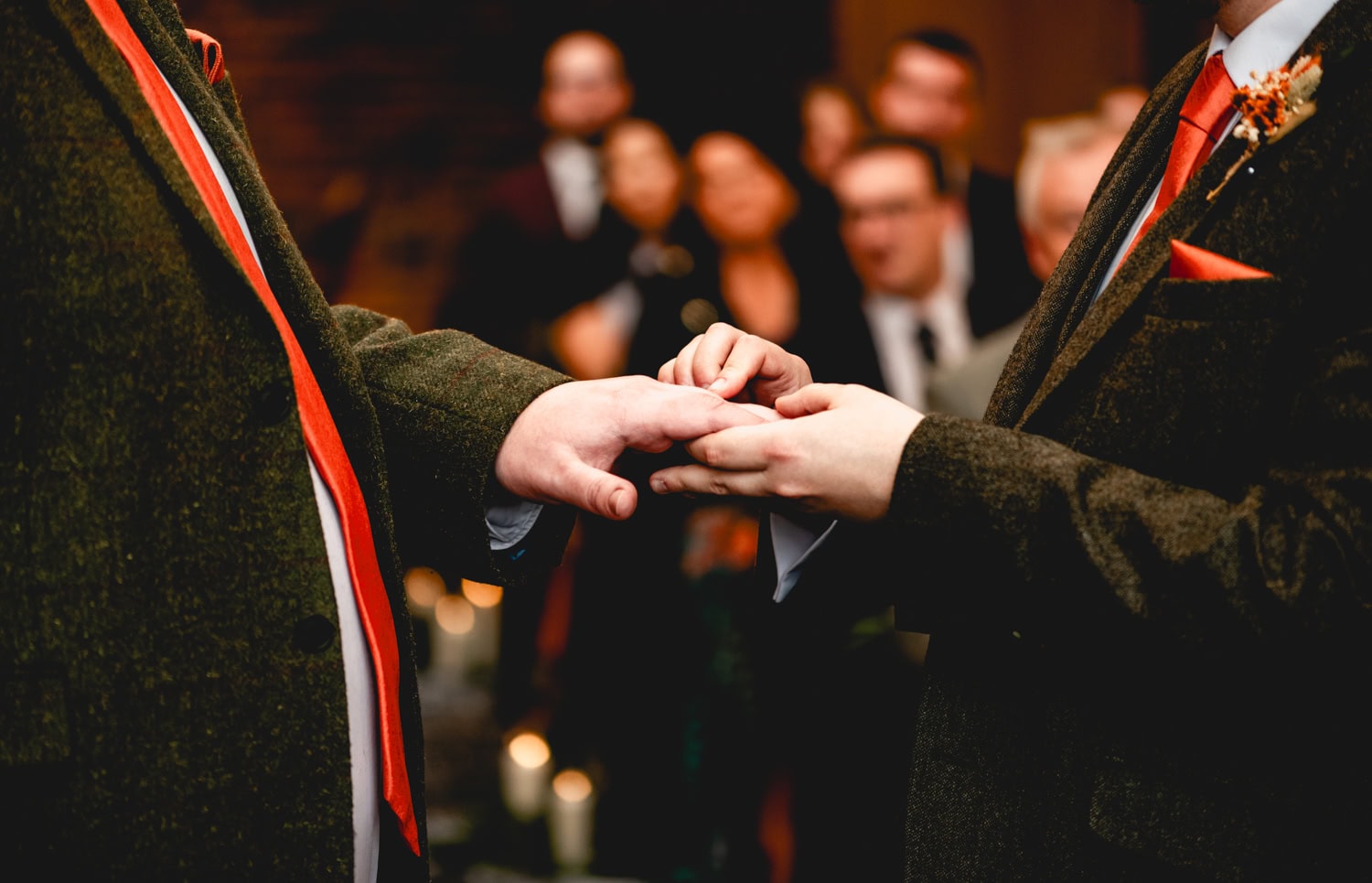 Two hands exchanging rings at a same sex wedding in a barn venue
